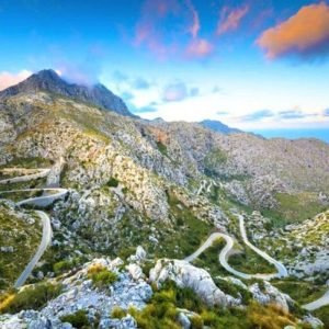 Winding mountain road with hairpin bends on the way to Sa Calobra at sunset, with the sea in the distance