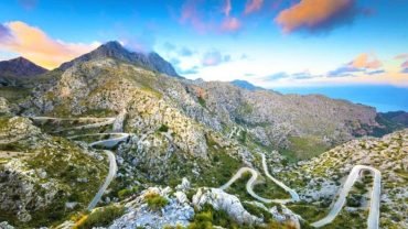 Winding mountain road with hairpin bends on the way to Sa Calobra at sunset, with the sea in the distance