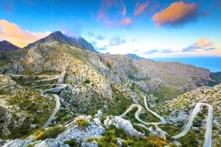 Winding mountain road with hairpin bends on the way to Sa Calobra at sunset, with the sea in the distance
