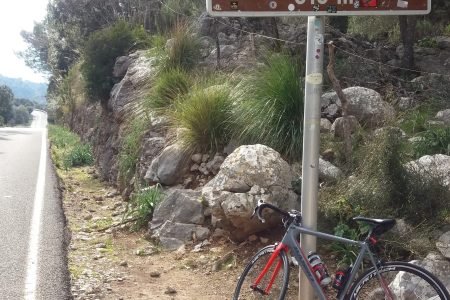 Road bike leaning against the Coll de Femenia 515 m sign beside the road