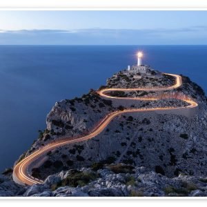 Formentor lighthouse at dusk with light trails along the winding road to the cape, above the sea
