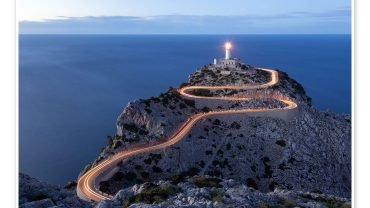 Formentor lighthouse at dusk with light trails along the winding road to the cape, above the sea