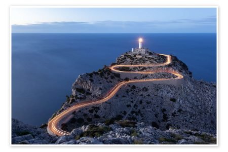 Formentor lighthouse at dusk with light trails along the winding road to the cape, above the sea