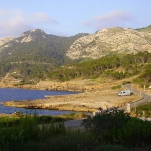 Rocky coast and pine-covered mountain at La Victoria with a road running along the sea