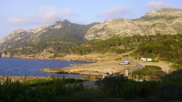 Rocky coast and pine-covered mountain at La Victoria with a road running along the sea