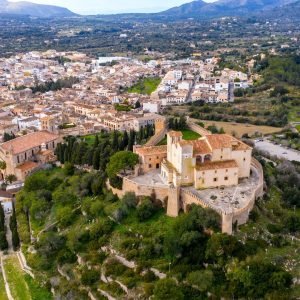 Aerial view of the fortified hilltop sanctuary above the town of Artà, with mountains in the distance
