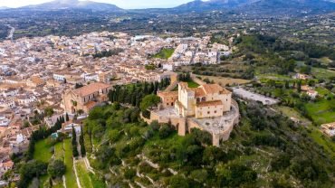 Aerial view of the fortified hilltop sanctuary above the town of Artà, with mountains in the distance