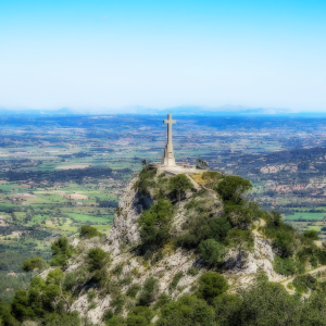 Stone cross on a rocky hilltop at Puig de Sant Salvador with views over the plains of Mallorca