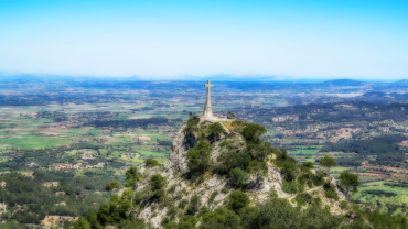 Stone cross on a rocky hilltop at Puig de Sant Salvador with views over the plains of Mallorca